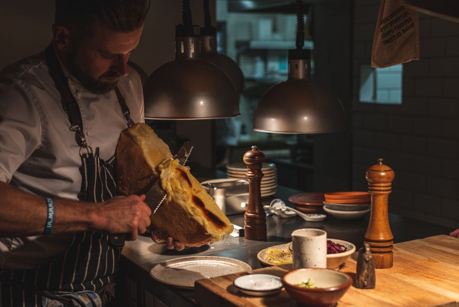 A chef preparing some cheese at Aroleid, a contemporary mountain restaurant in Zermatt. 