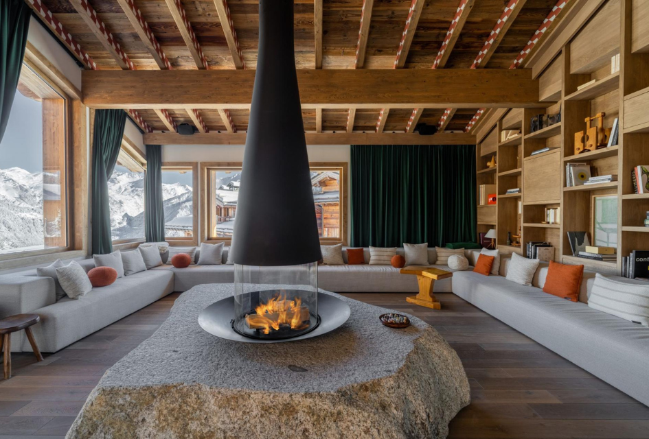 Living room of Chalet Le 1550, with a stunning mountain view and central fireplace.