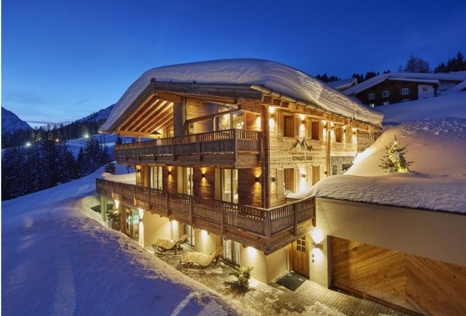 Lit up night-time exterior of Chalet 1551, one of the best luxury ski chalets in Austria. Overlooking the mountains and slopes in Lech