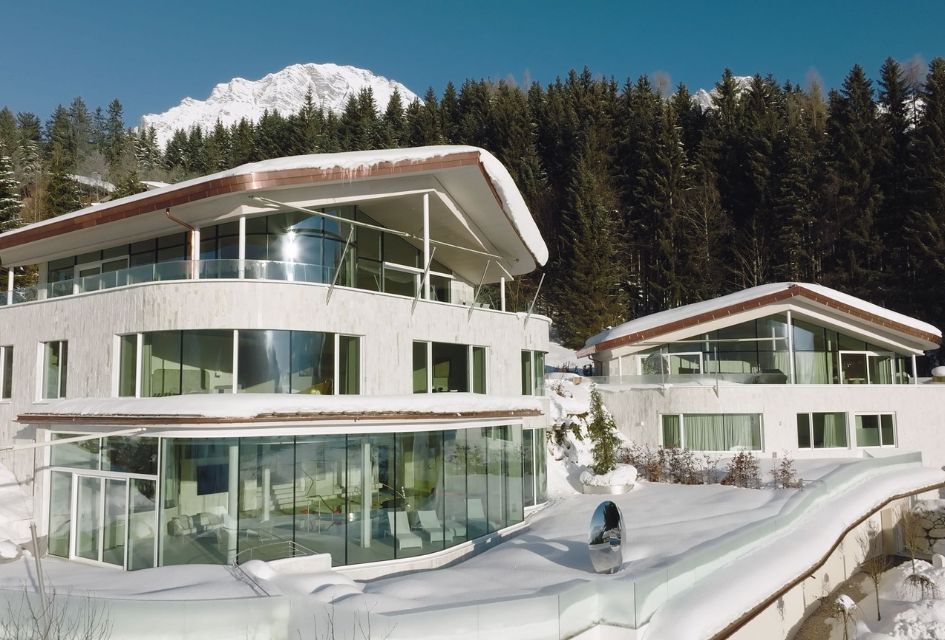 Julisam Estate, a pair of large luxury ski chalets in Austria, with blue skies and snow surrounding, in Leogang.