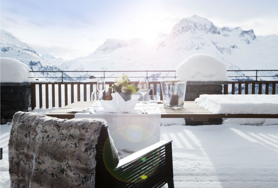 Terrace of Chalet N, looking out at the Austrian Alps with a stylish statue of a stag and sun loungers visible