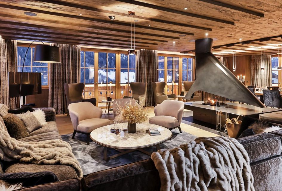 Living room of Chalet Lena in St Anton, with a modern central fireplace and comfortable sofas, with mountain views from the windows.