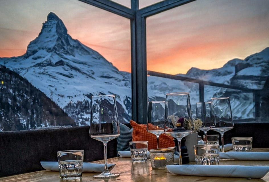 Matterhorn sunset view from the terrace of Findlerhof, one of the best restaurants in Zermatt, with wine glasses and a laid table in the foreground.